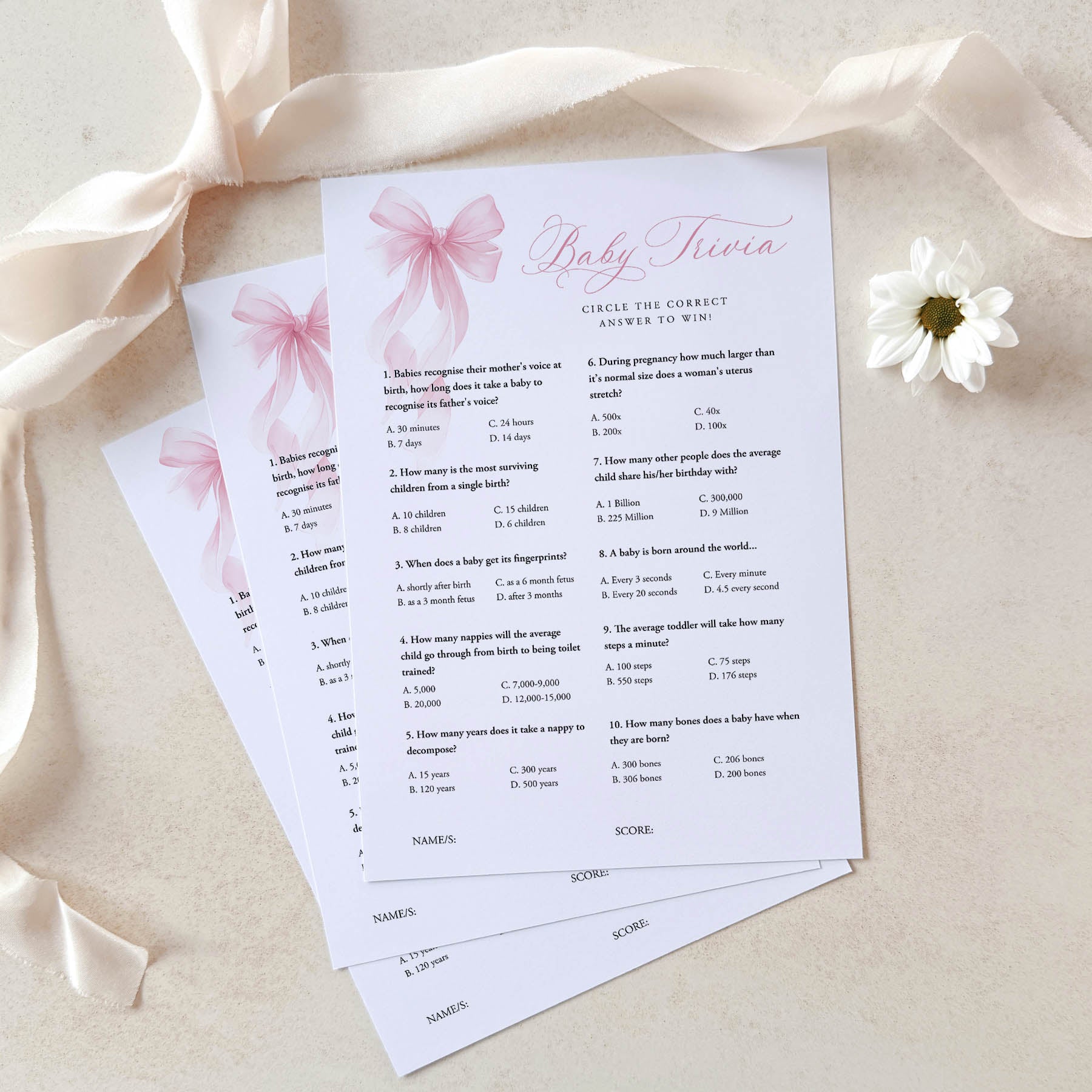 Baby trivia game cards with pink bows and a flower on a beige background