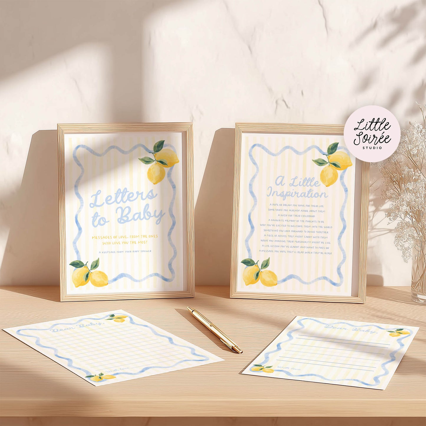 Framed prints with lemon illustrations and stationery on a wooden surface.