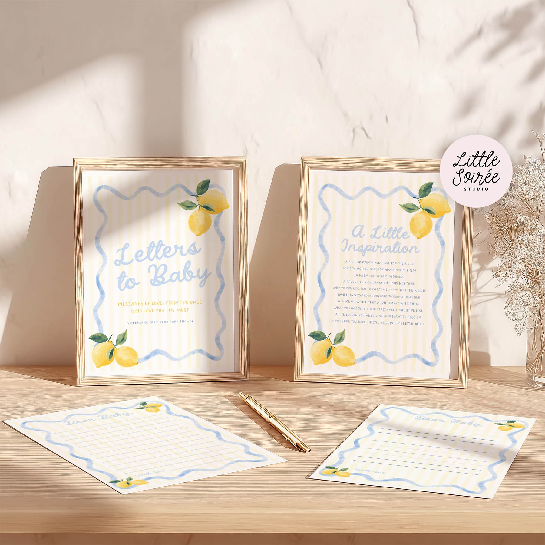 Framed prints with lemon illustrations and stationery on a wooden surface.