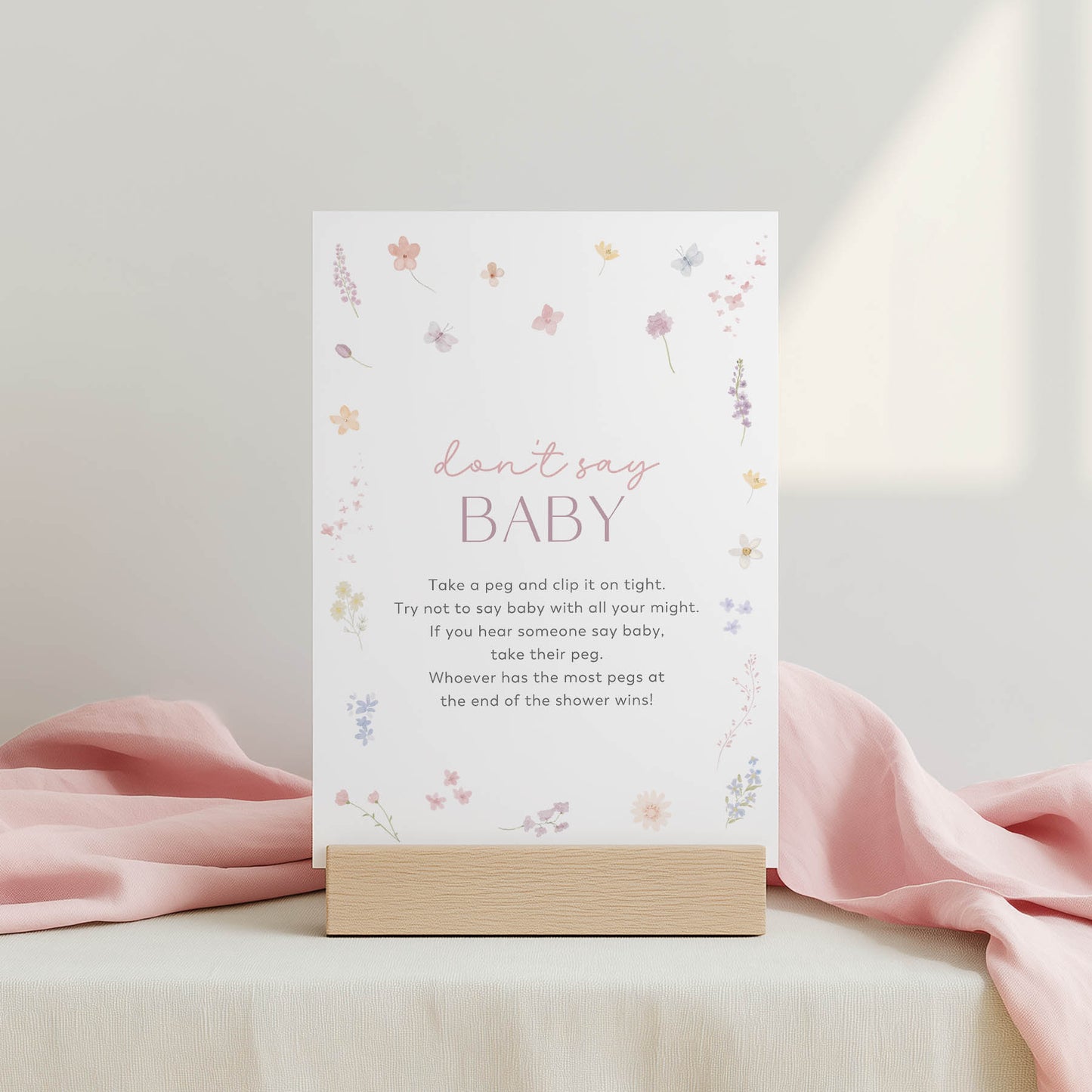 Card with text and floral design on a stand with pink fabric in the background