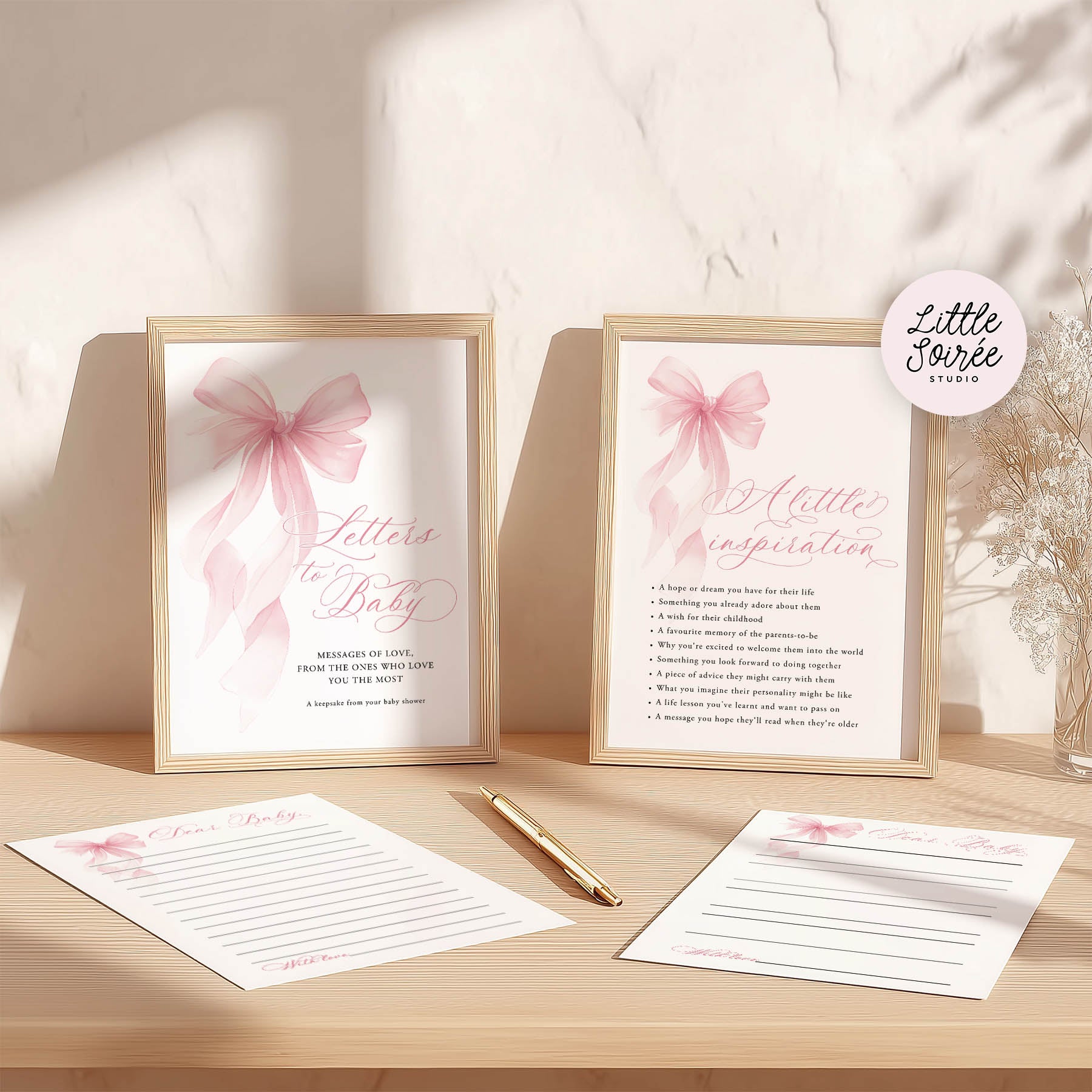 Framed prints with pink bows and writing paper on a wooden surface, featuring 'Little Sorrel Studio' branding.