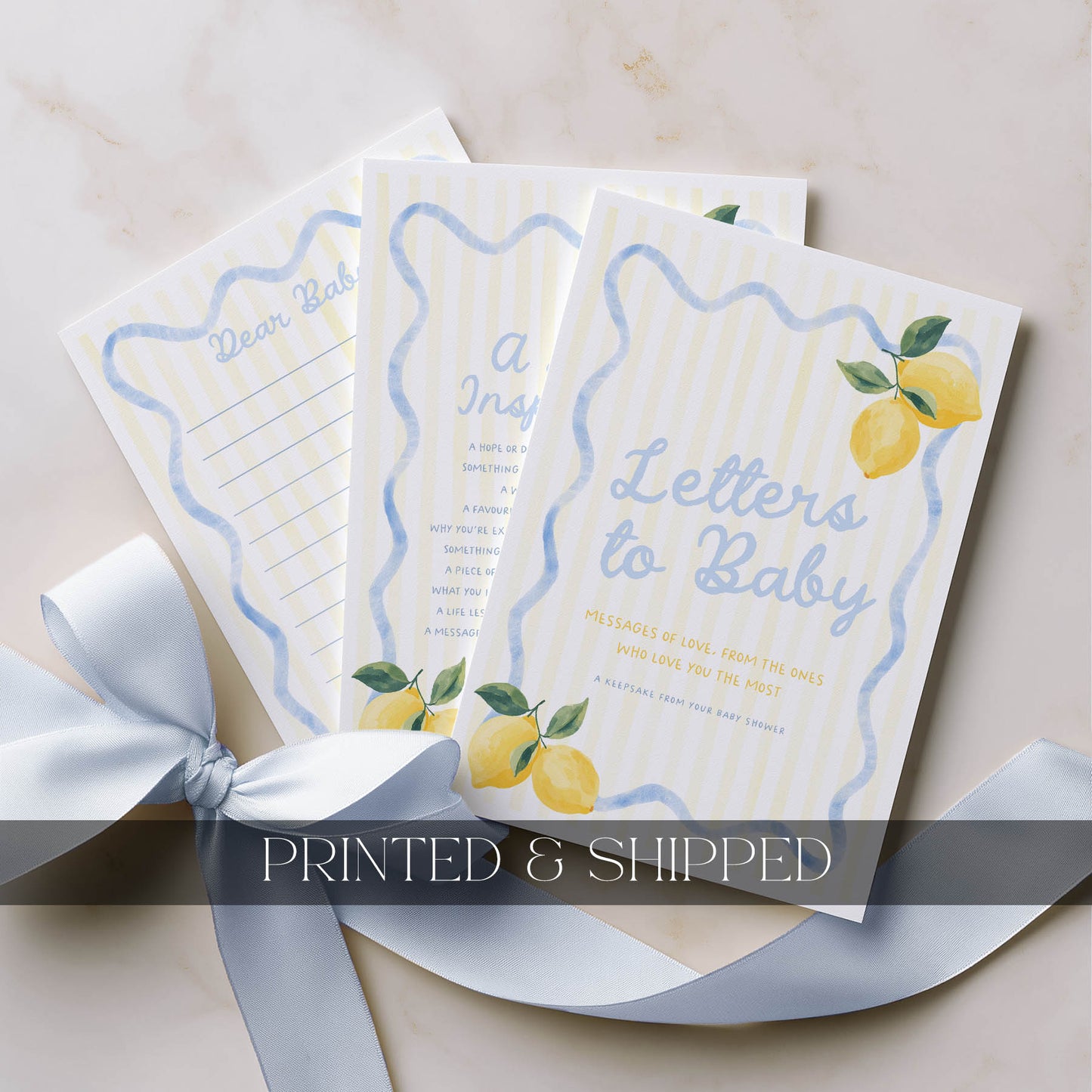Three 'Letters to Baby' books with lemon illustrations on a beige surface with a white ribbon.