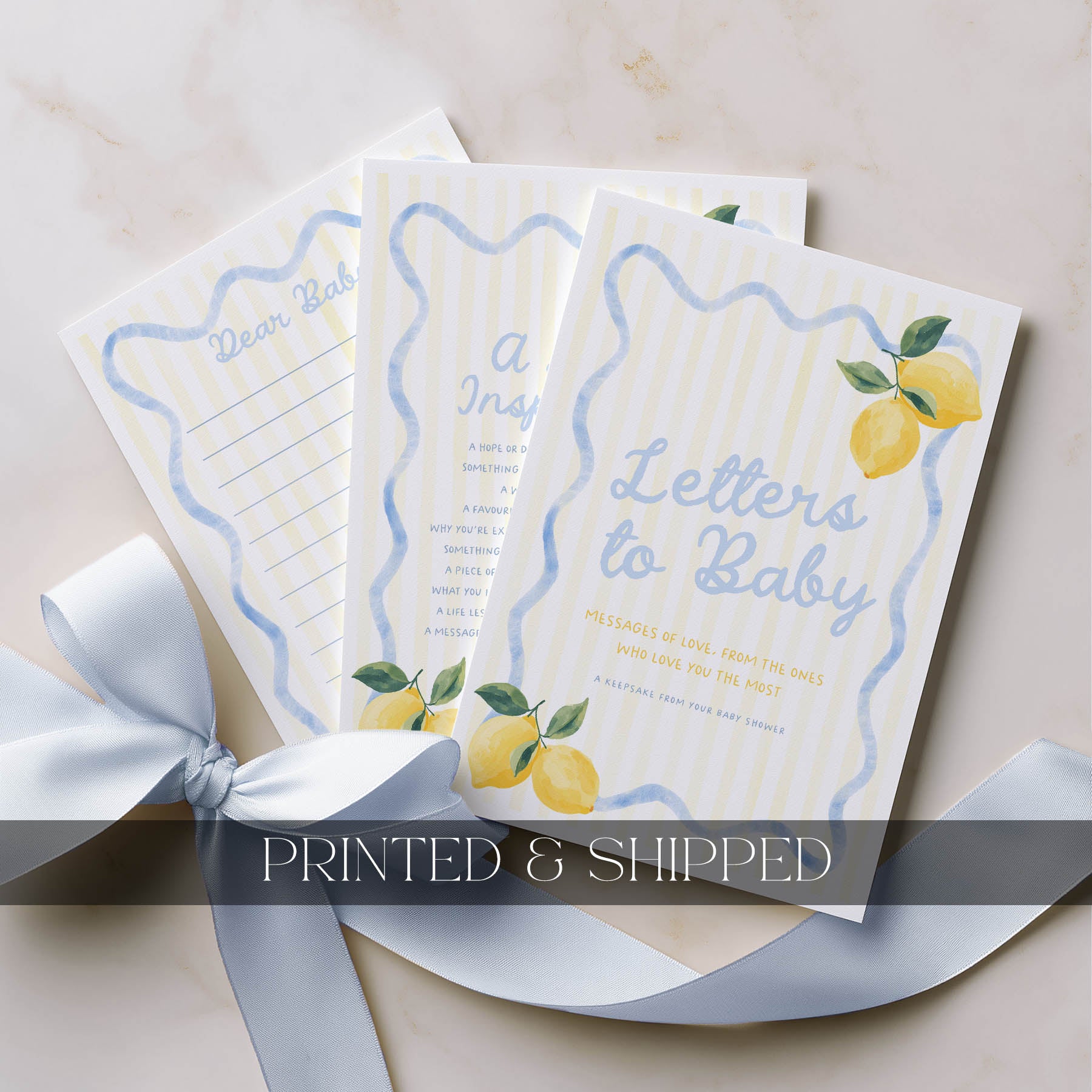 Three 'Letters to Baby' books with lemon illustrations on a beige surface with a white ribbon.