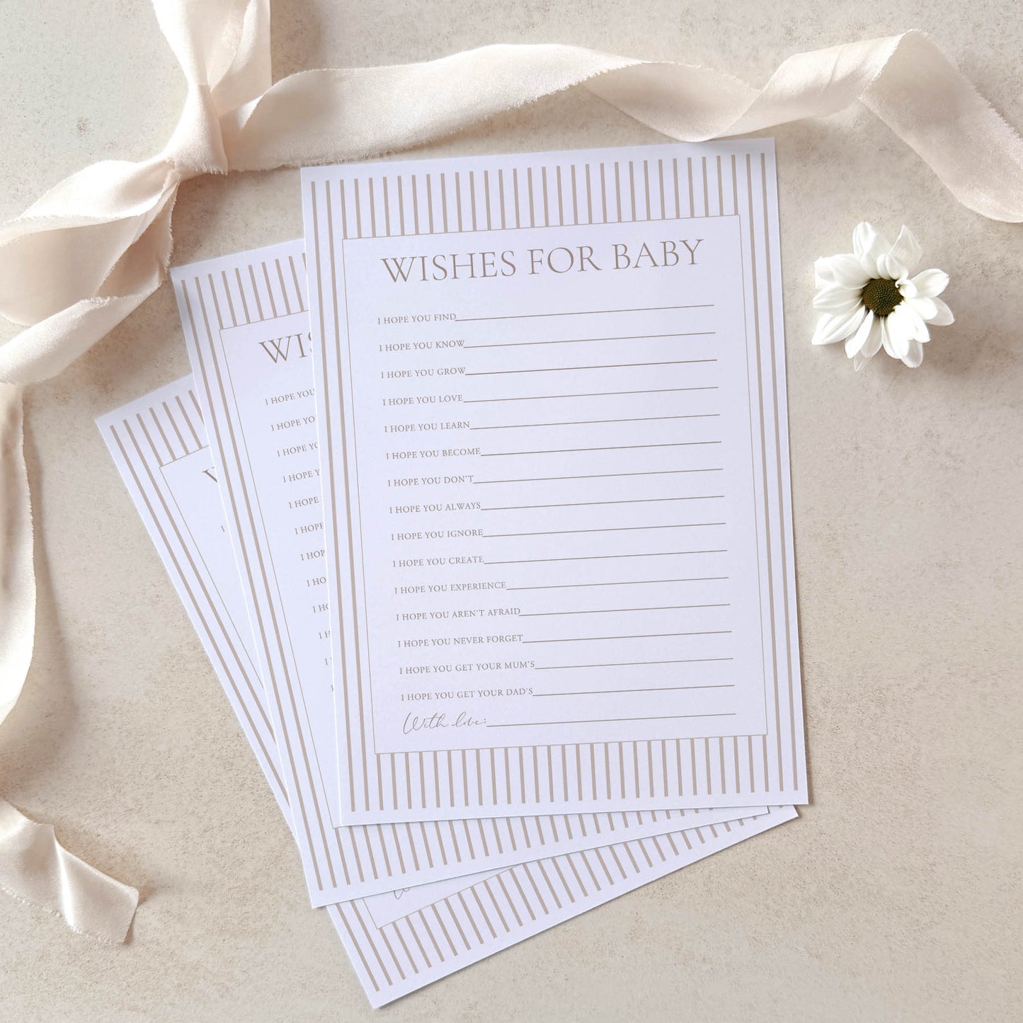 Sheet of paper with 'Wishes for Baby' text on a beige background with ribbons and a flower.