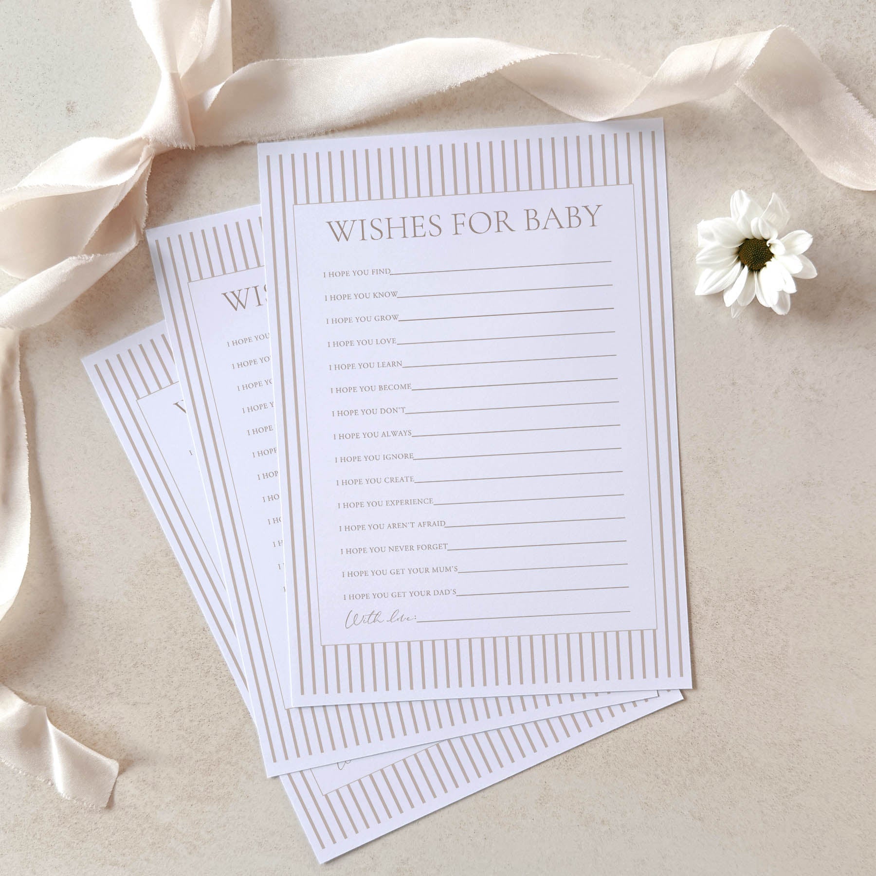 Sheet of paper with 'Wishes for Baby' text on a beige background with ribbons and a flower.
