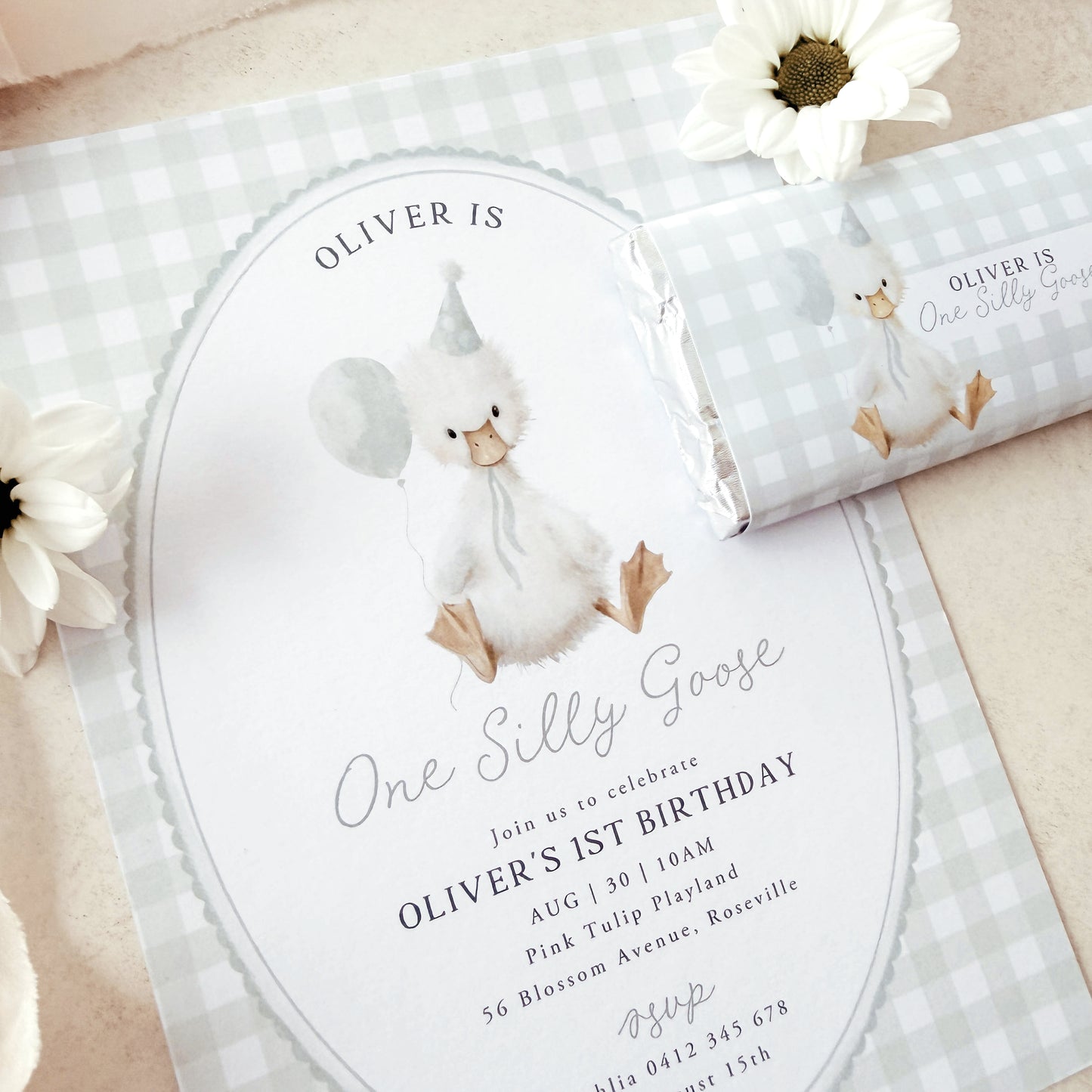 Invitation card with a goose illustration and text for a birthday celebration, accompanied by a matching swaddle blanket.