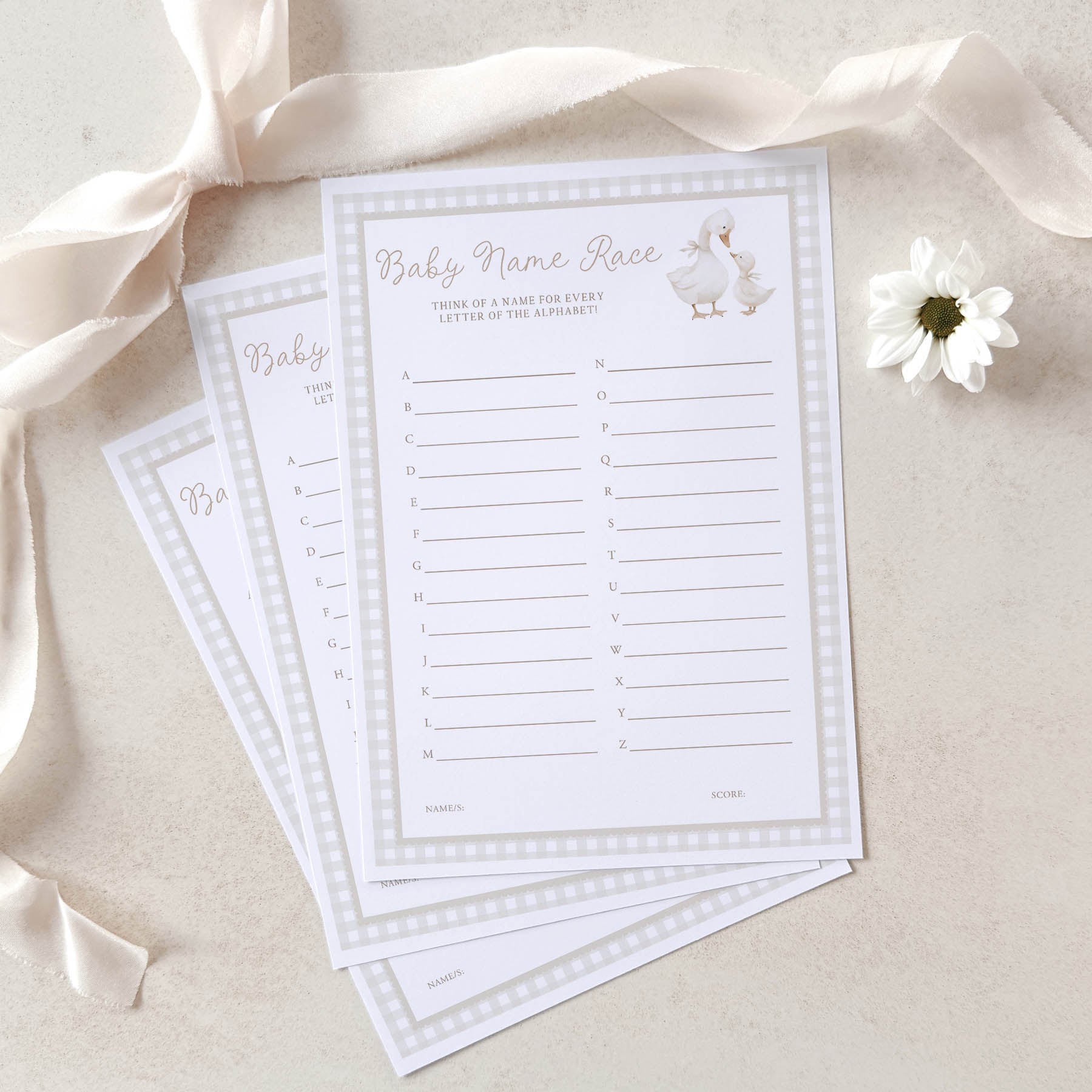 Baby name race game cards with a white ribbon and flower on a beige background