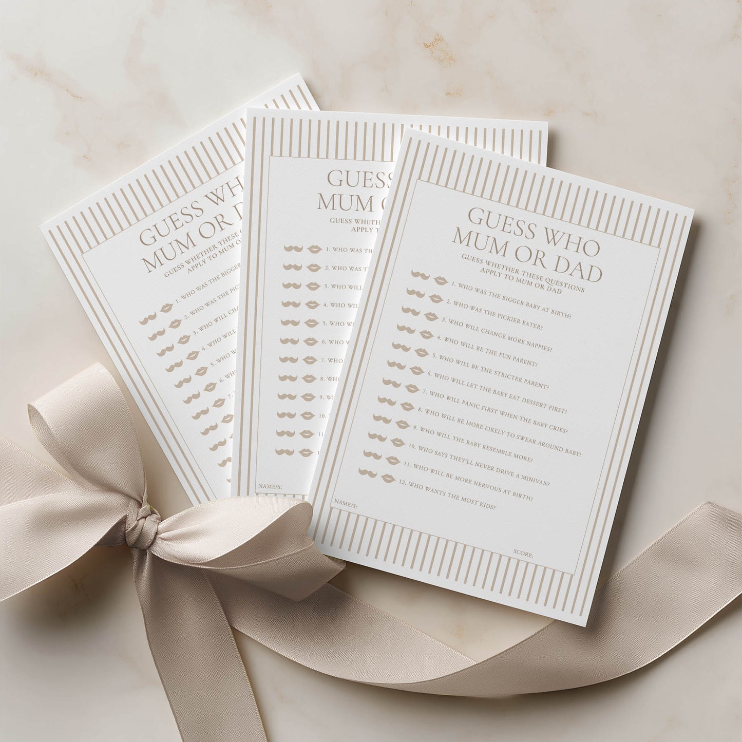 Three 'Guess Who Mum or Dad' cards with a ribbon on a beige background