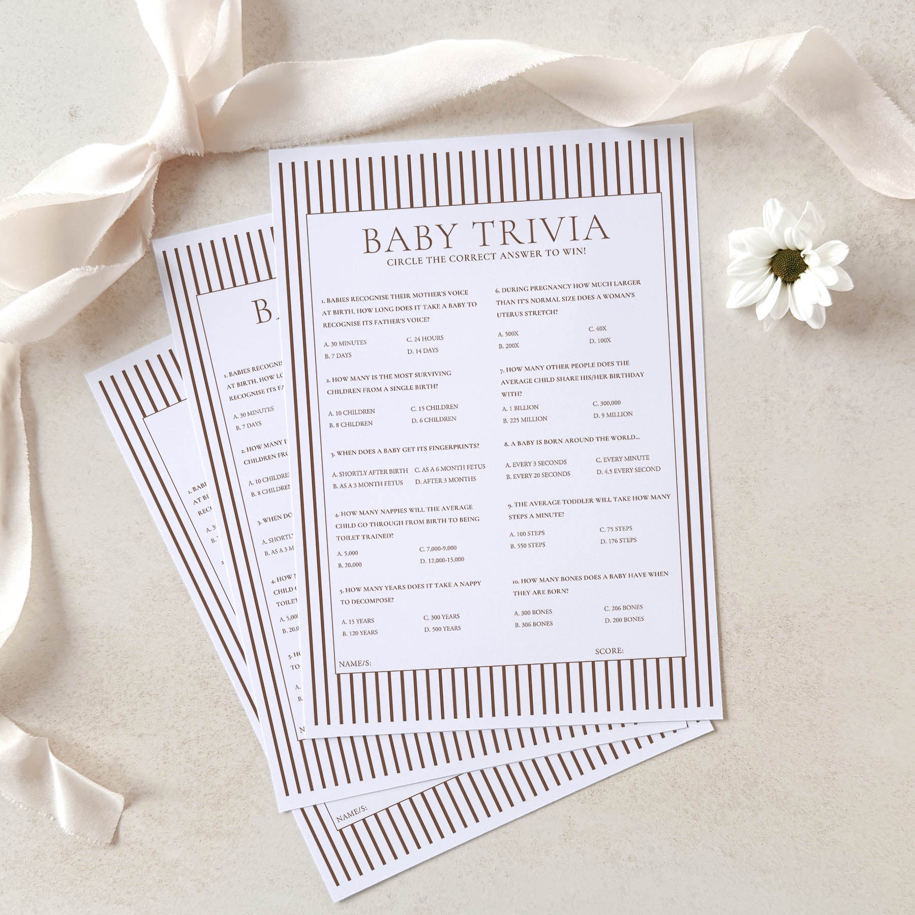 Baby trivia game cards on a light background with ribbons and a flower.