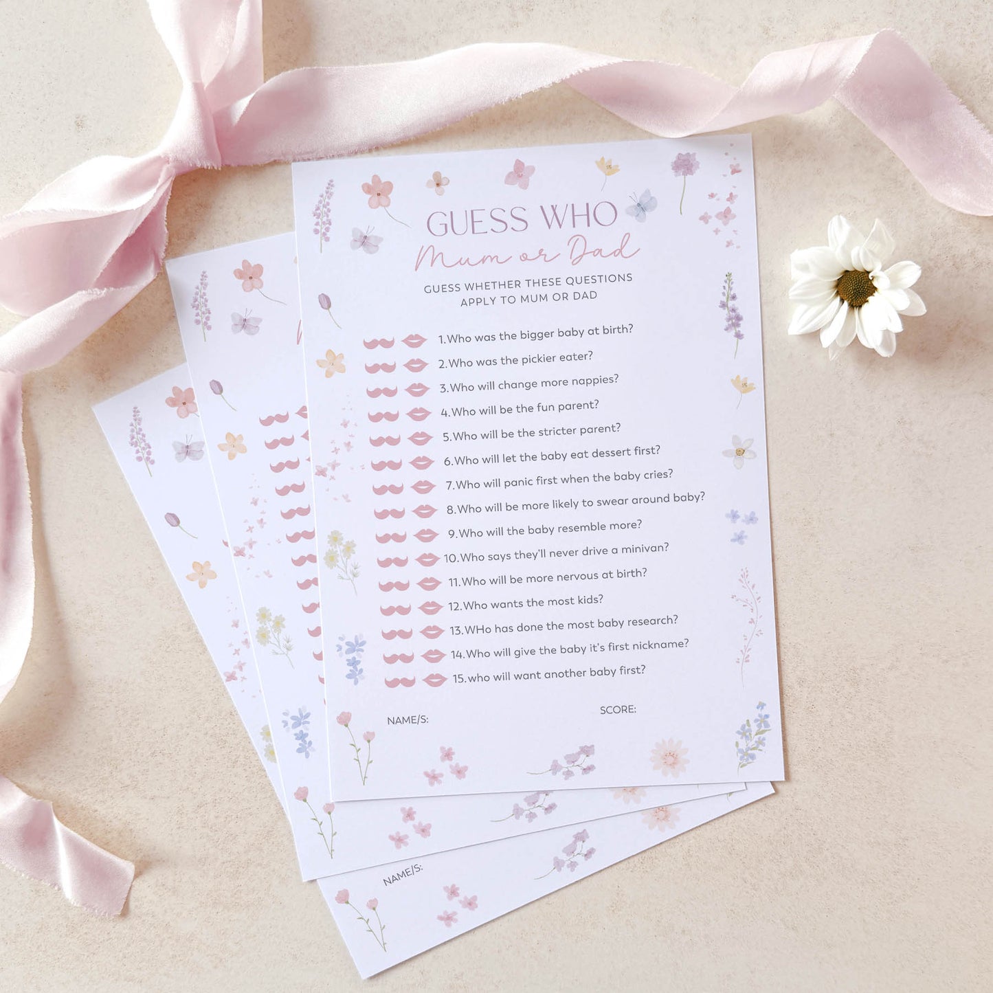 Baby shower game cards with floral design on a beige background with pink ribbon and white flower.