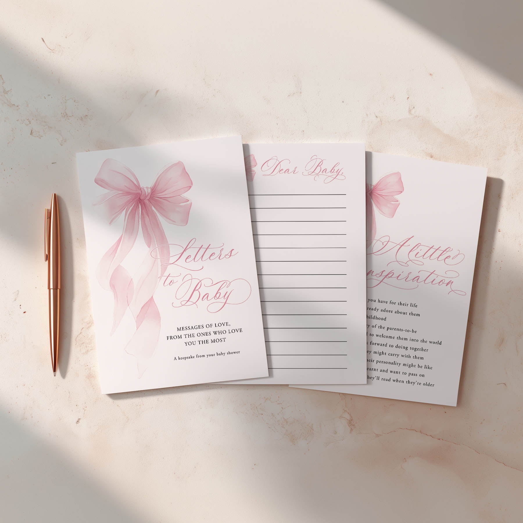 Set of baby shower cards with pink bows and a pen on a light surface