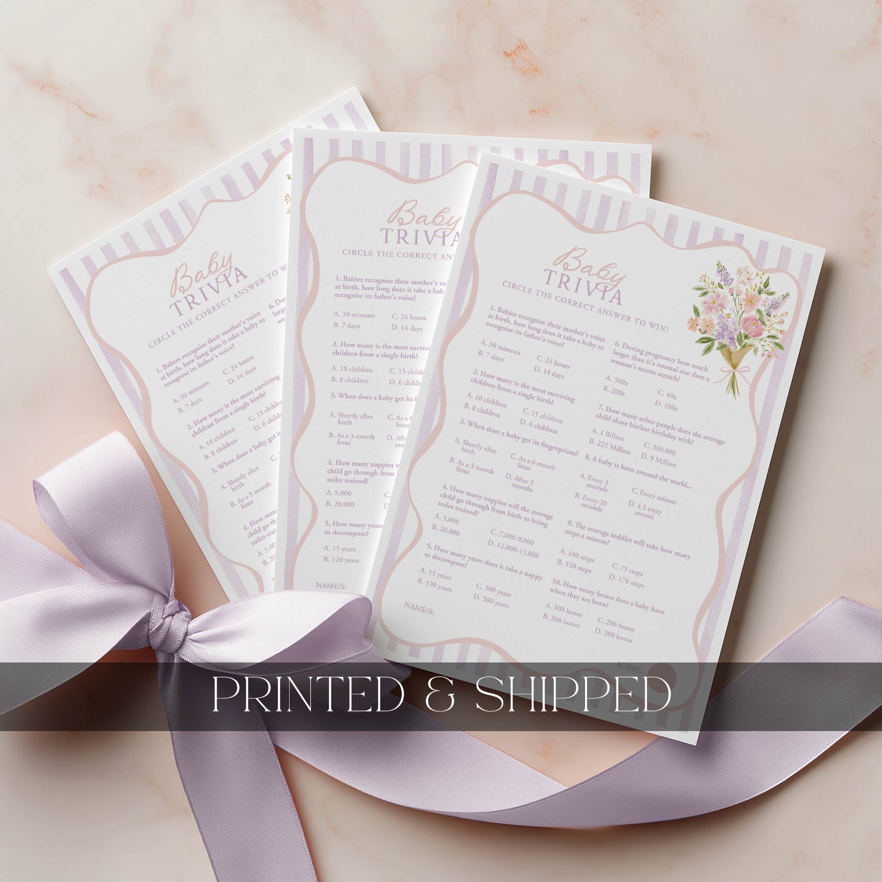 Three printed wedding games with floral designs on a beige surface with a pink ribbon.