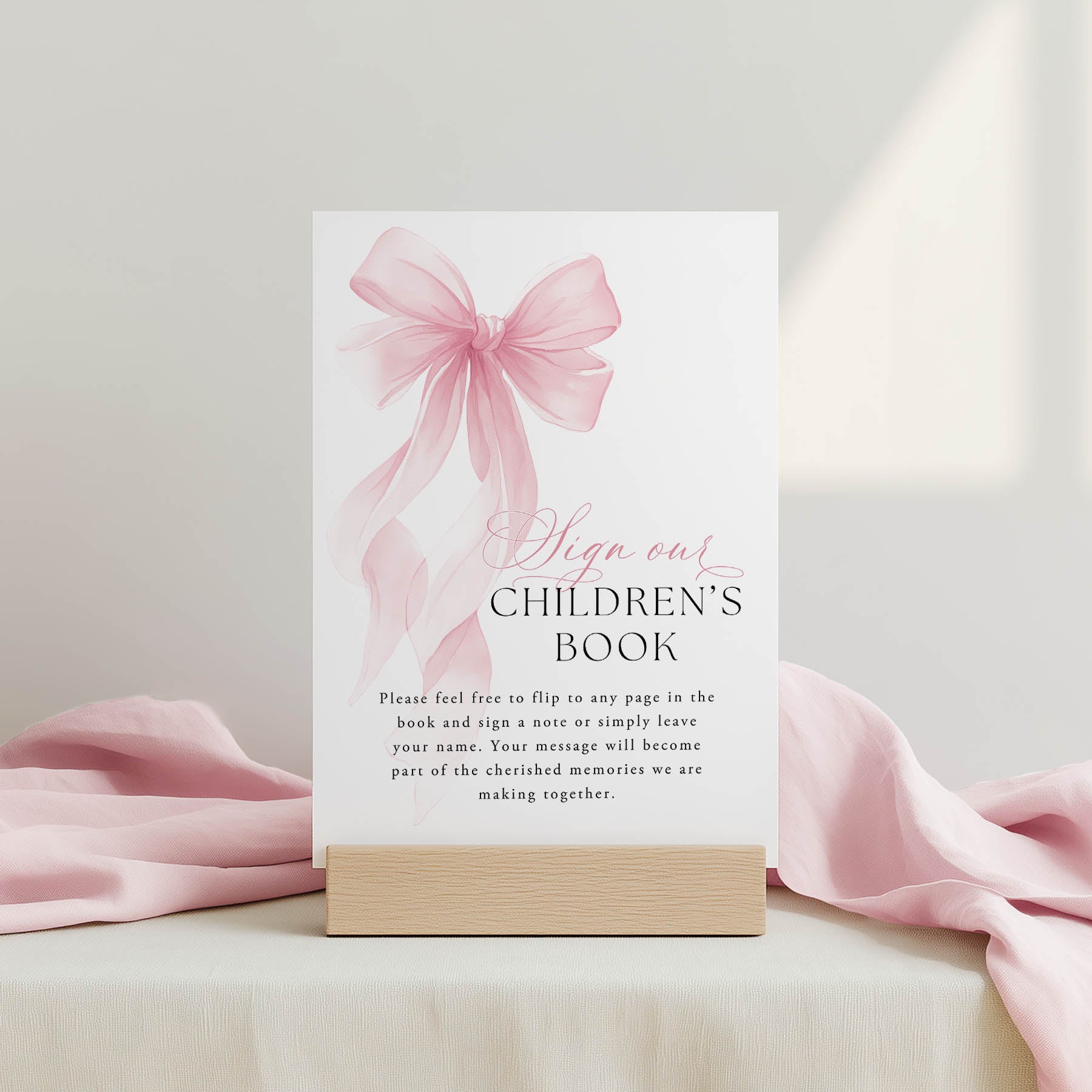 Children's book sign-out card with pink bow and stand on a light background