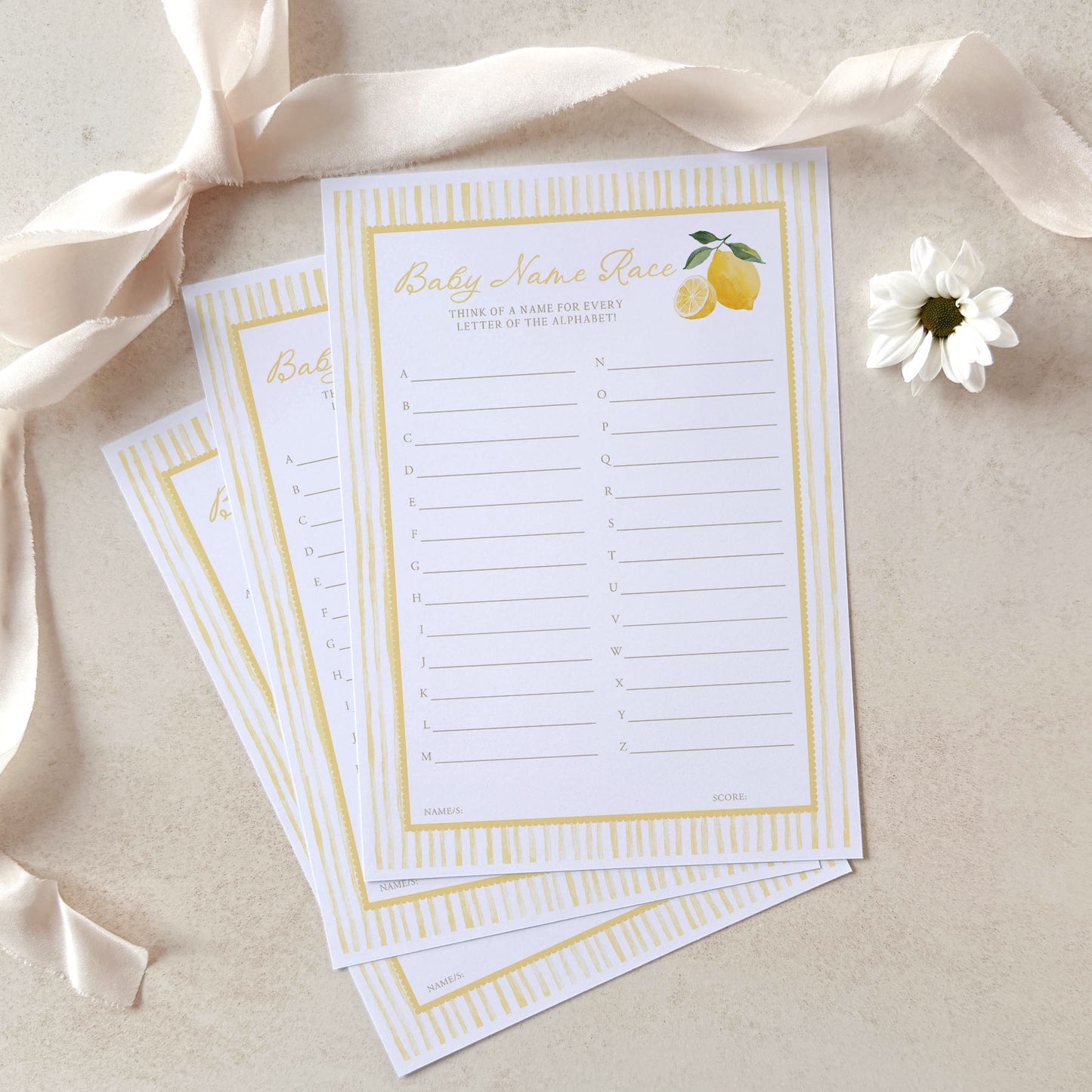 Baby name game cards with gold border and lemon illustration on a beige background with ribbon and flower.