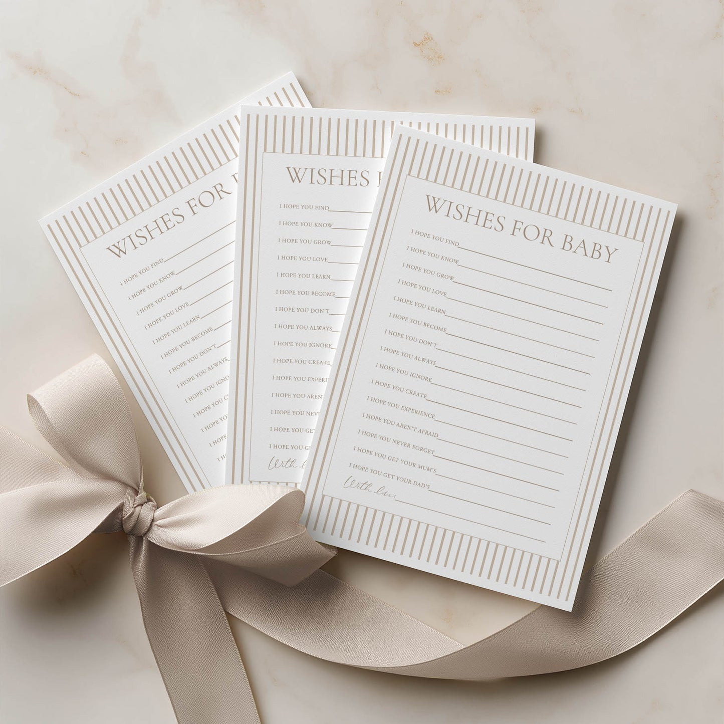Three 'Wishes for Baby' cards with a ribbon on a beige surface