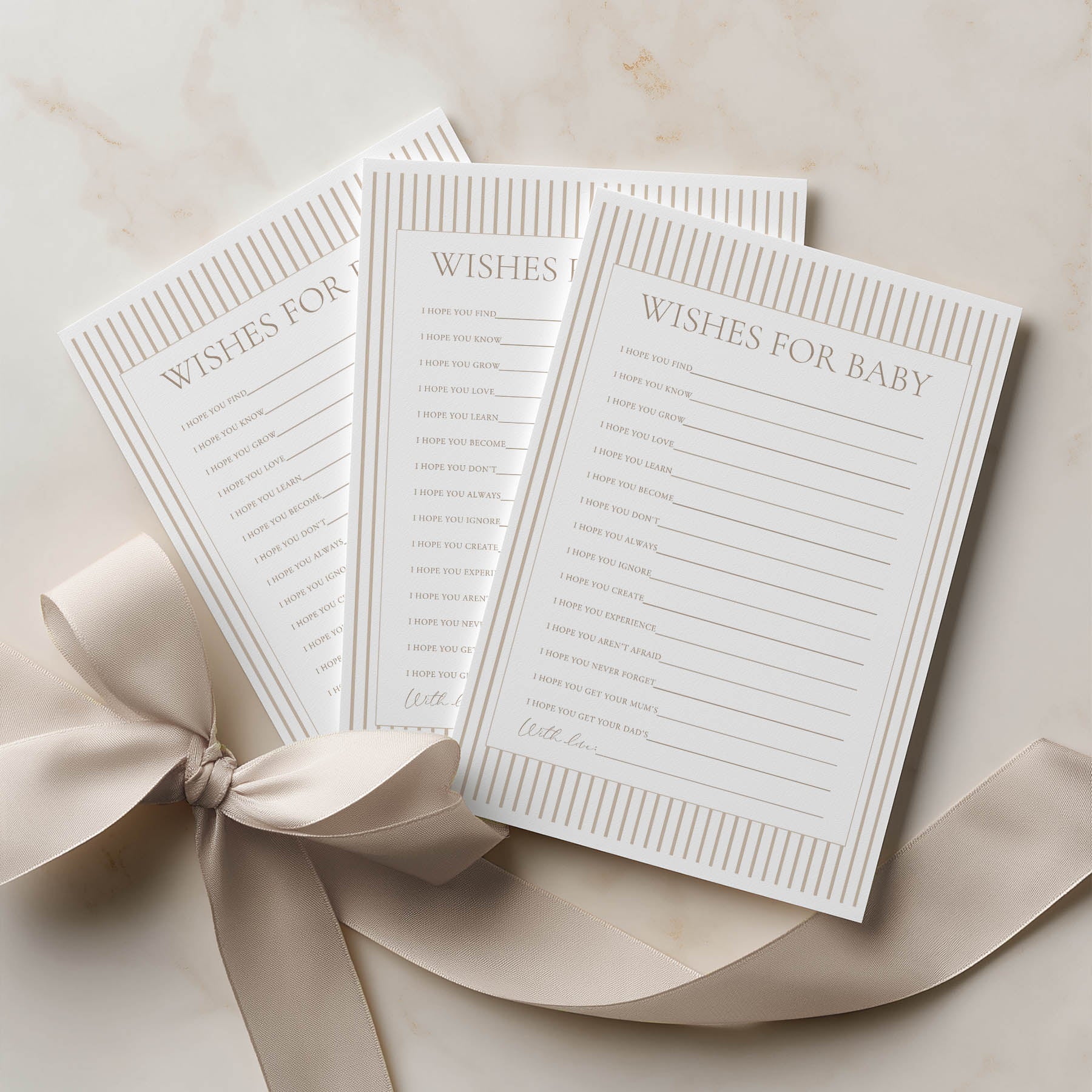 Three 'Wishes for Baby' cards with a ribbon on a beige surface
